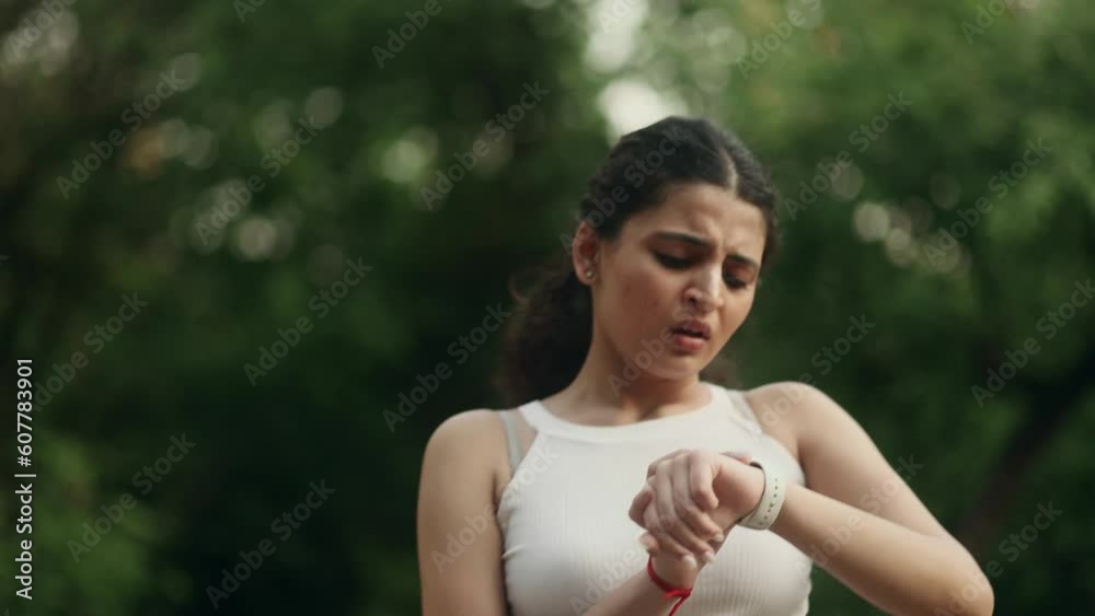 Athlete indian girl finish her running at park and upset while checking bad result on smart watch tracker bracelet Tired sporty young woman jogging with fail problem no progress in training outdoors Athlete indian girl finish her running at park and upset while checking bad result on smart watch tracker bracelet Tired sporty young woman jogging with fail problem no progress in training outdoors