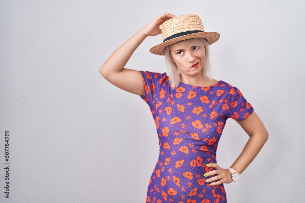 Young caucasian woman wearing flowers dress and summer hat confuse and wondering about question. uncertain with doubt, thinking with hand on head. pensive concept. Young caucasian woman wearing flowers dress and summer hat confuse and wondering about question. uncertain with doubt, thinking with hand on head. pensive concept.