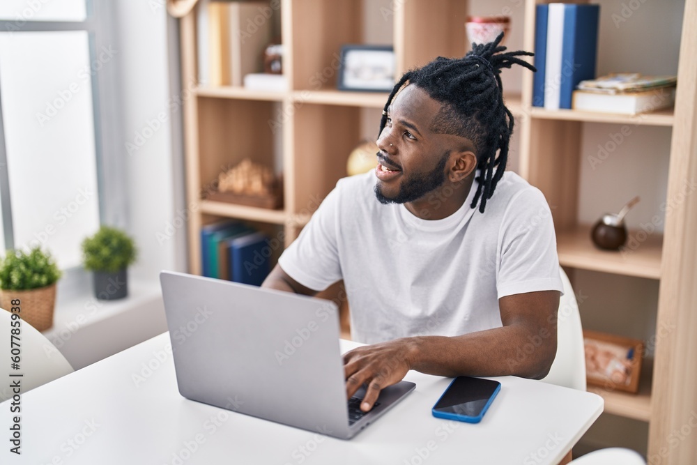 African american woman using laptop sitting on table at home African american woman using laptop sitting on table at home