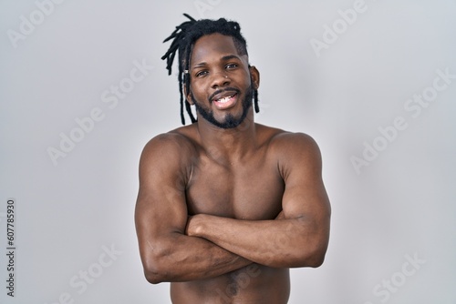 African man with dreadlocks standing shirtless over isolated background happy face smiling with crossed arms looking at the camera. positive person.