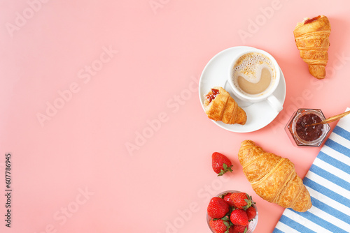 Delicious breakfast with fresh croissants, coffee, berry jam and fresh berries on a pink background. copy space.