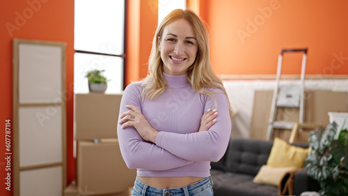 Young beautiful hispanic woman smiling confident standing with arms crossed gesture at new home