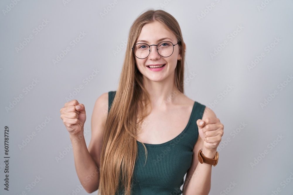 Young caucasian woman standing over white background very happy and excited doing winner gesture with arms raised, smiling and screaming for success. celebration concept. Young caucasian woman standing over white background very happy and excited doing winner gesture with arms raised, smiling and screaming for success. celebration concept.