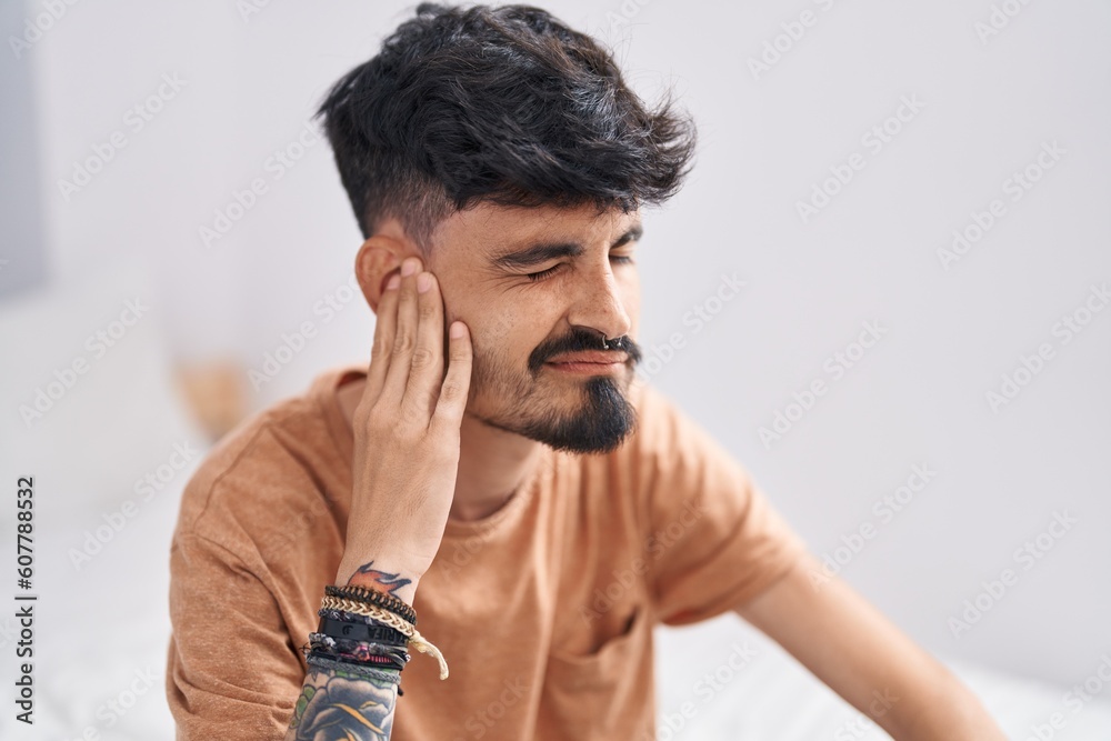 Young hispanic man suffering for ear pain at bedroom Young hispanic man suffering for ear pain at bedroom
