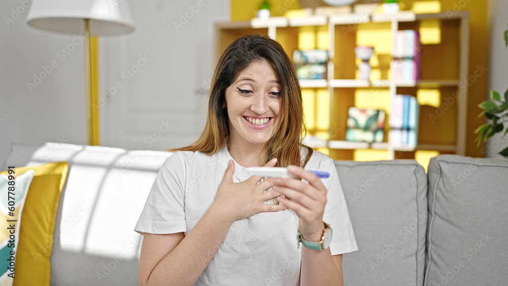 Young blonde woman holding pregnancy test with surprise expression at home Young blonde woman holding pregnancy test with surprise expression at home
