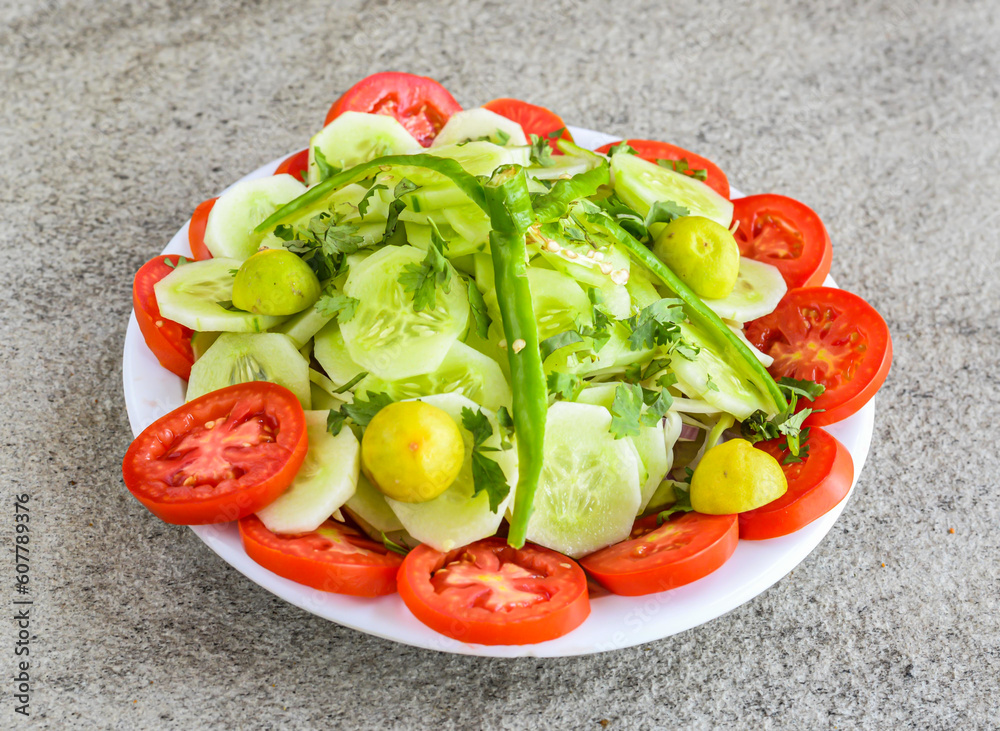green fresh salad with tomato, cucumber, lemon served in plate isolated on grey background top view of pakistani and indian spices food green fresh salad with tomato, cucumber, lemon served in plate isolated on grey background top view of pakistani and indian spices food