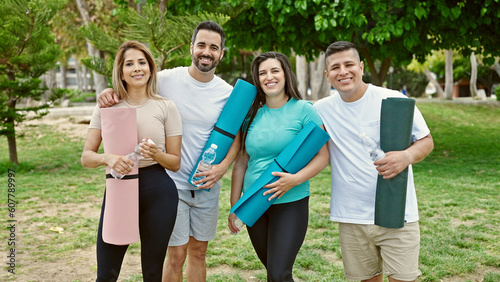 Group of people smiling confident holding yoga mat at park