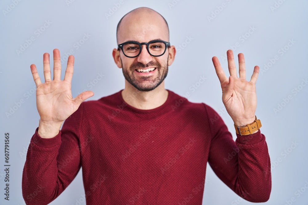 Naklejka premium Young bald man with beard standing over white background wearing glasses showing and pointing up with fingers number nine while smiling confident and happy.