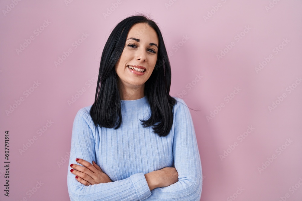 Fototapeta premium Hispanic woman standing over pink background happy face smiling with crossed arms looking at the camera. positive person.
