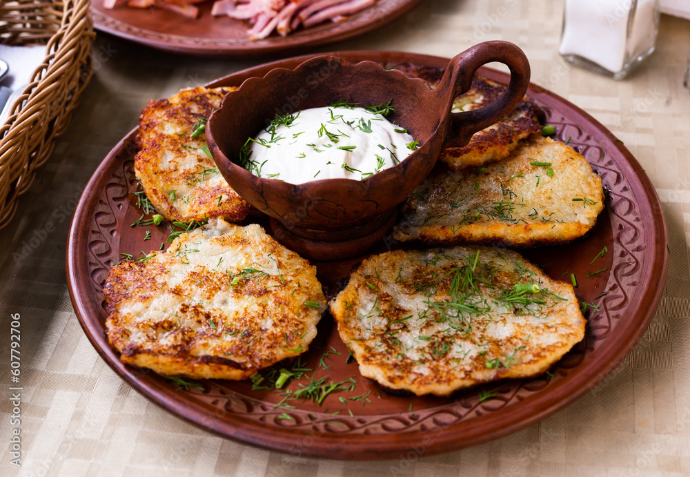 potato pancakes with sour cream and herbs on white plate potato pancakes with sour cream and herbs on white plate