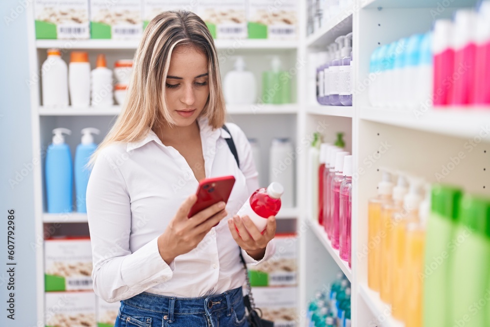 Young blonde woman customer using smartphone holding medicine bottle at pharmacy Young blonde woman customer using smartphone holding medicine bottle at pharmacy