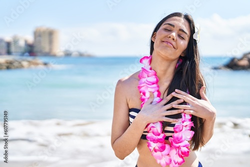 Young brunette woman wearing bikini at the beach smiling with hands on chest, eyes closed with grateful gesture on face. health concept.
