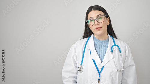 Young hispanic woman doctor standing with serious expression over isolated white background