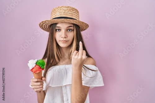 Teenager girl holding ice cream showing middle finger, impolite and rude fuck off expression