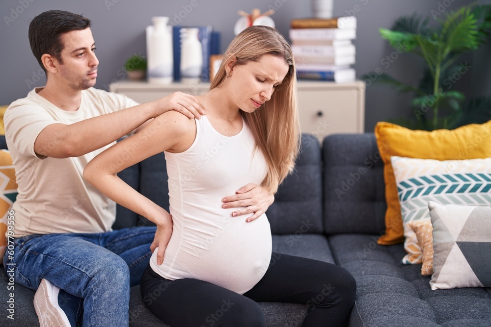 Obraz premium Man and woman couple expecting baby massaging back at home