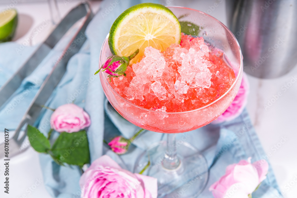 Frozen rose daiquiri or margarita cocktail, champagne, pink rose wine alcohol drink with roses flowers and lime slices