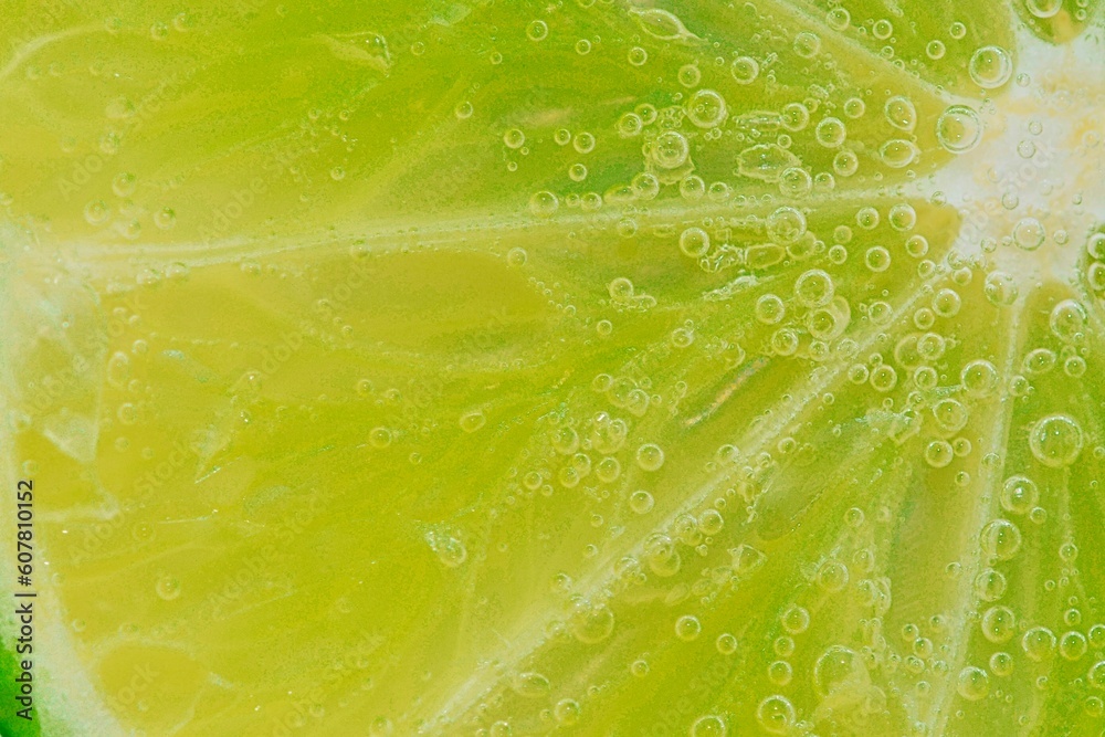 Slice of ripe lime in water. Close-up of lime in liquid with bubbles. Slice of ripe lime in sparkling water. Macro horizontal image of fruit in carbonated water. Slice of ripe lime in water. Close-up of lime in liquid with bubbles. Slice of ripe lime in sparkling water. Macro horizontal image of fruit in carbonated water.