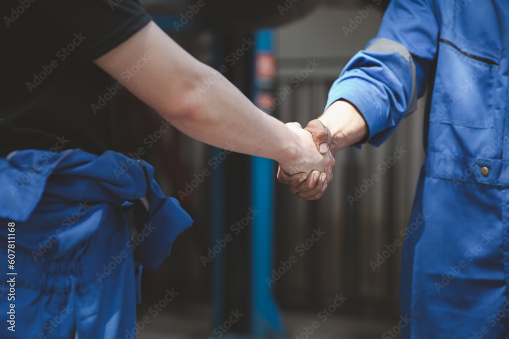 Two professional auto mechanics shaking hands, all kinds of car specialists, expert auto repair and standard auto repair center.