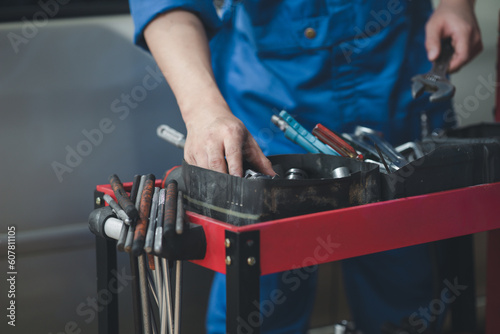 Professional car mechanics searching for auto repair tools in tool racks, all kinds of auto specialists, expert auto repair and accredited auto repair centers.