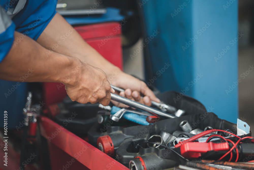 Professional car mechanics searching for auto repair tools in tool racks, all kinds of auto specialists, expert auto repair and accredited auto repair centers.
