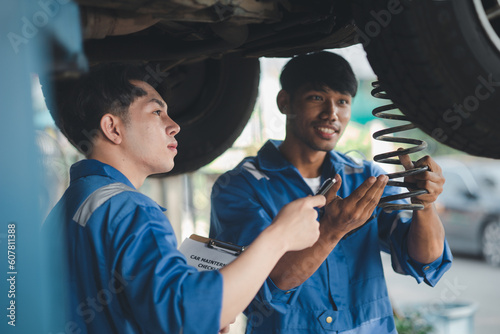 Two professional car mechanics helping to repair shock absorbers and car suspension, all kinds of car experts, expert auto repair and accredited auto repair center. © kamiphotos