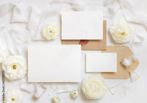 Blank cards and envelopes near cream roses and white ribbons top view, wedding mockup