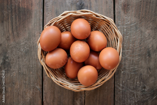 Close-up view of raw chicken eggs in egg basket on brown wooden background