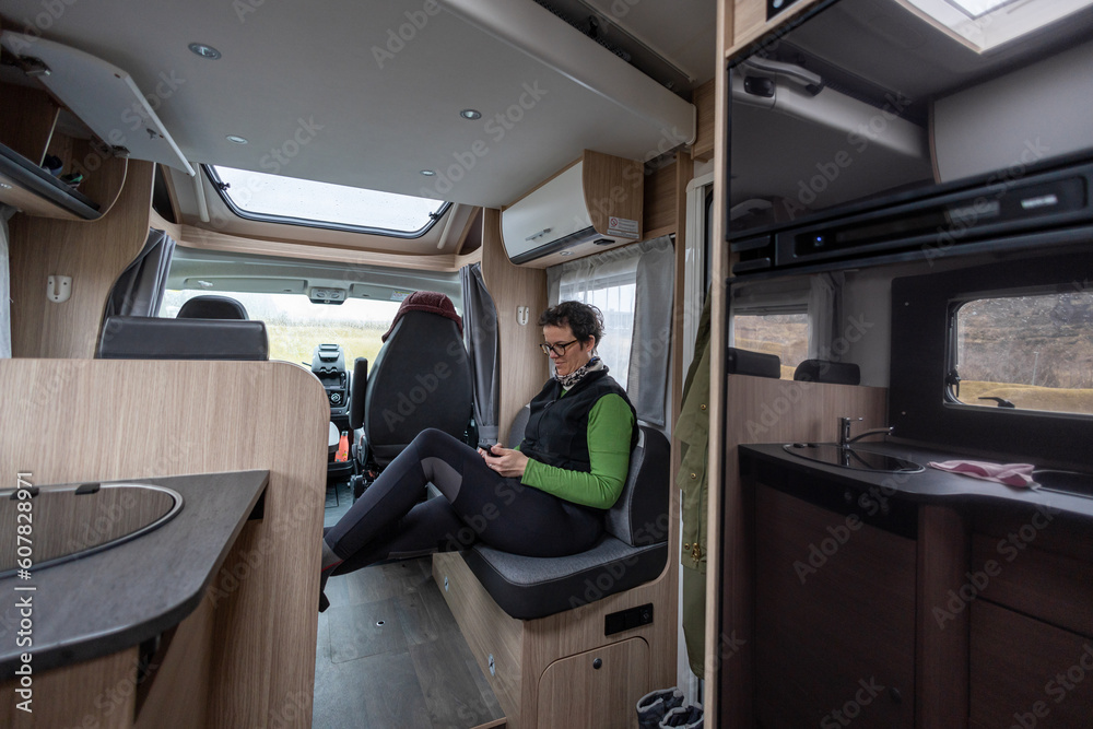 Caucasian woman looking at the smartphone inside the caravan on the road to iceland Caucasian woman looking at the smartphone inside the caravan on the road to iceland