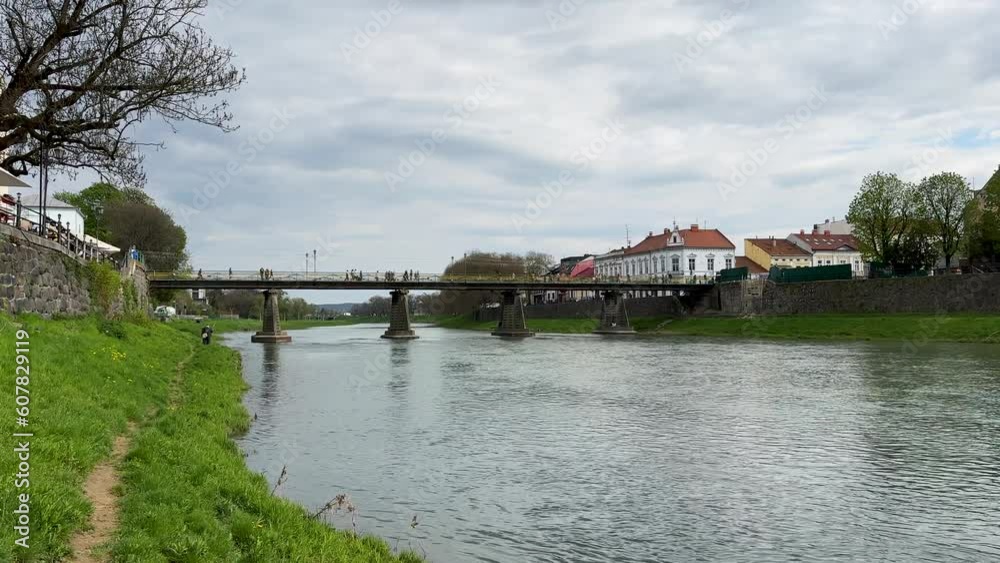Scenic spring view of the river Uzh and a pedestrian bridge across it with busy traffic Scenic spring view of the river Uzh and a pedestrian bridge across it with busy traffic