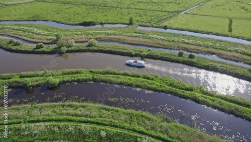 Aerial shot of a broads cruiser motoring along the River Bure, Norfolk Broads National Park. Captured on a sunny summer's evening photo