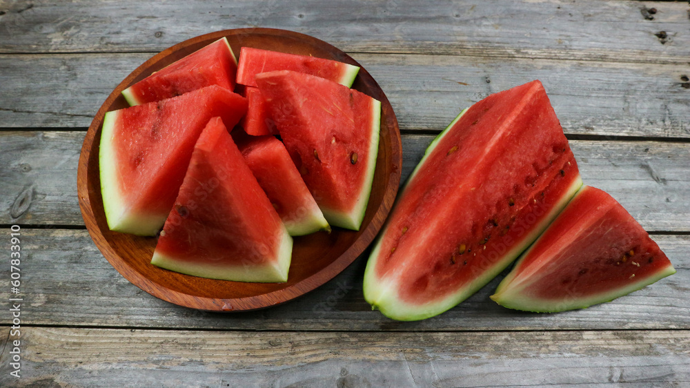 Red watermelon slices on wooden plate and isolated on gray board background. Healthy food, vegan. Antioxidant Red watermelon slices on wooden plate and isolated on gray board background. Healthy food, vegan. Antioxidant
