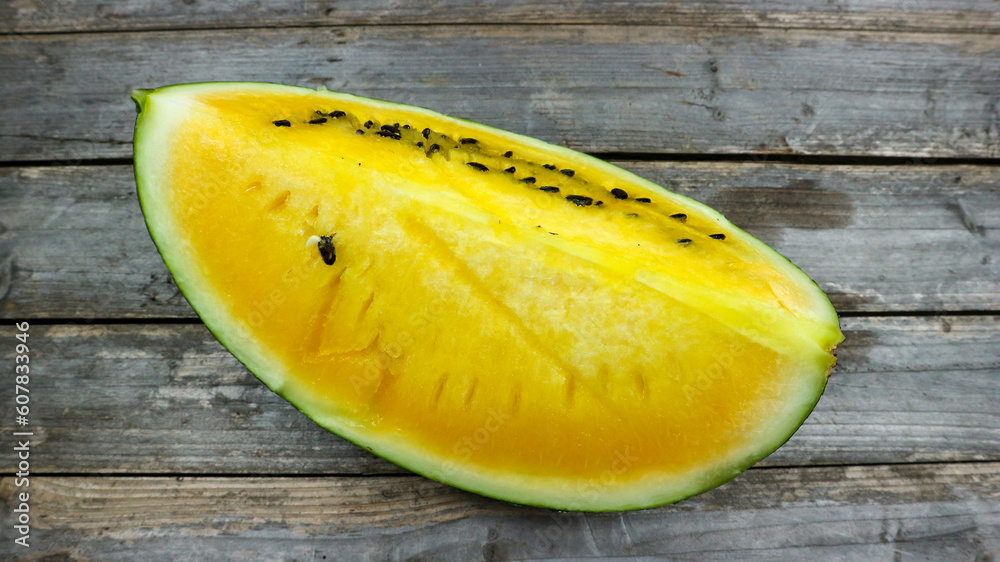 Yellow watermelon slices on wooden plate and isolated on gray board background. Healthy food, vegan. Antioxidant Yellow watermelon slices on wooden plate and isolated on gray board background. Healthy food, vegan. Antioxidant