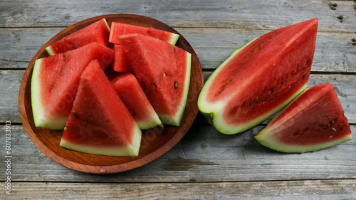 Red watermelon slices on wooden plate and isolated on gray board background. Healthy food, vegan. Antioxidant