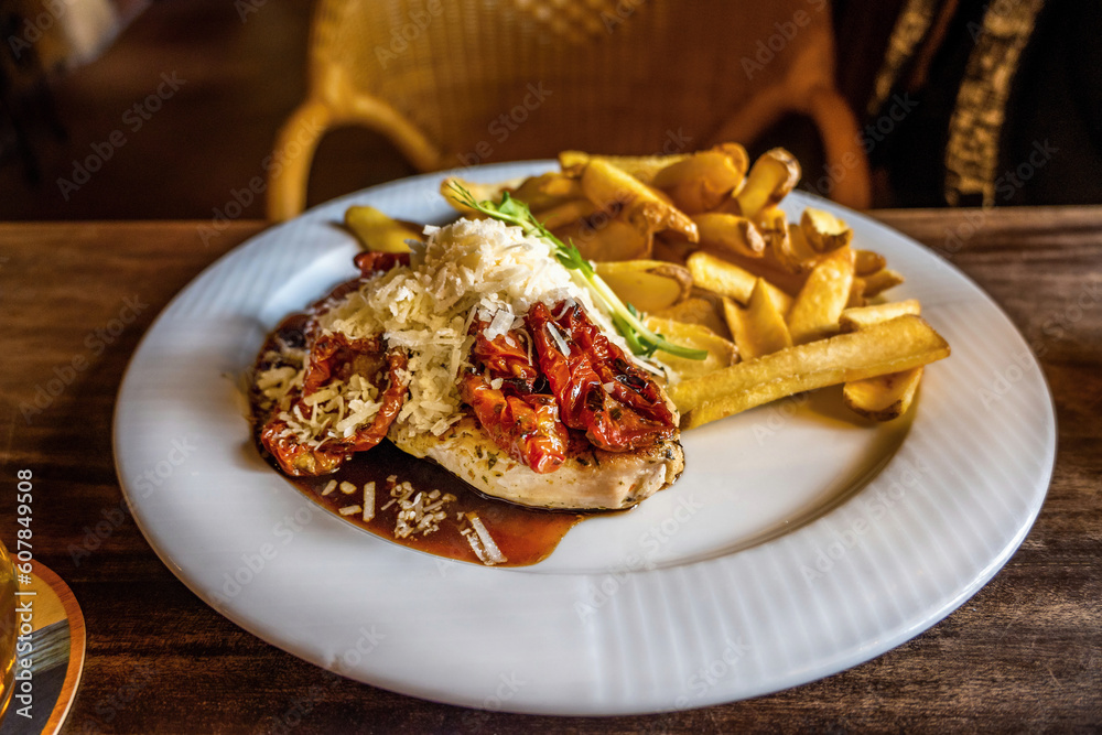Chicken fillet with dried tomato and grated cheese with french fries. Chicken fillet with dried tomato and grated cheese with french fries.