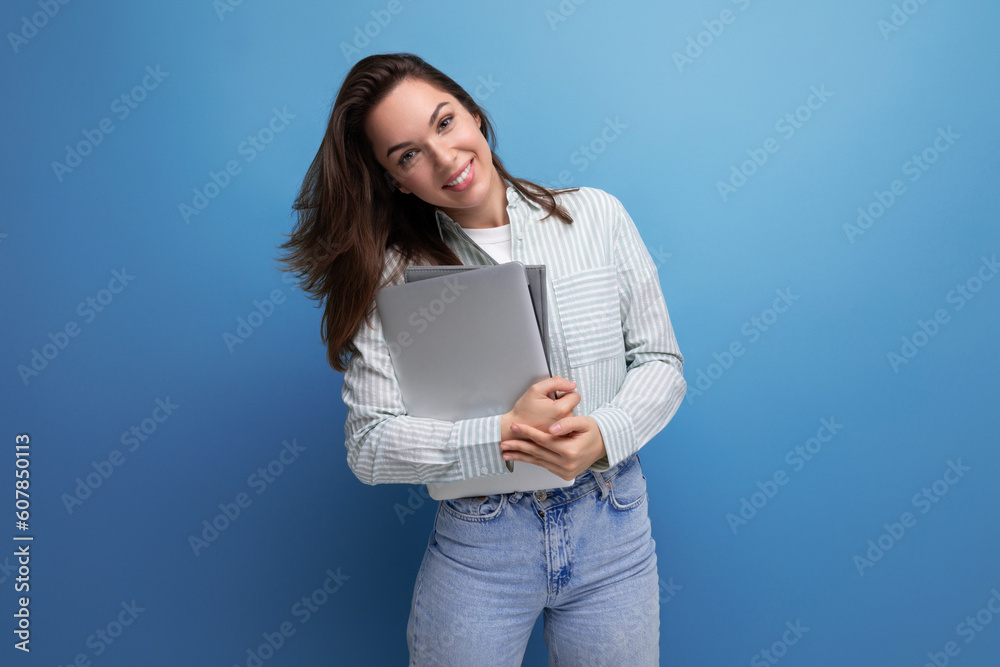 successful 20s brunette lady in shirt and jeans holding work laptop and papers successful 20s brunette lady in shirt and jeans holding work laptop and papers