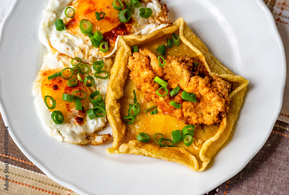 Fried egg and salty pancake with fried elderflower on white plate. Fried egg and salty pancake with fried elderflower on white plate.
