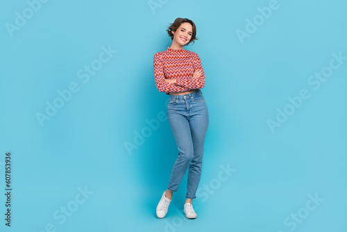 Full body portrait of confident lady hold arms crossed wear print crop shirt denim pants white sneakers isolated blue color background