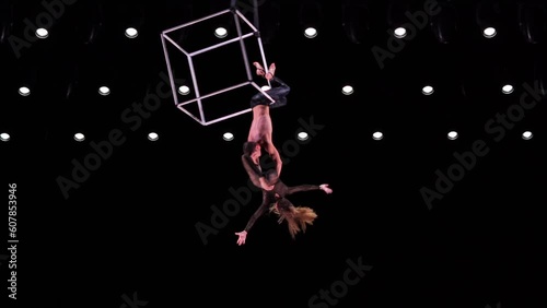 Aerial cube duo on black background perform risky trick. Concept of trust in relationship of couple 