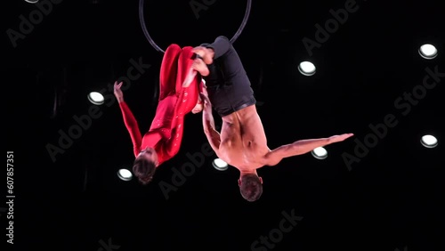 Aerial hoop duo on black background doing performance. Concept of romantic relationship in couple 