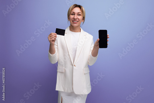 young european blonde business woman in a white jacket and dress holding a card and phone mockup