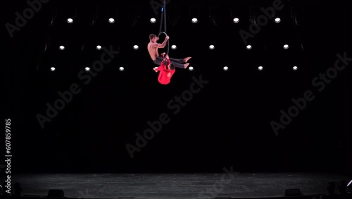 Aerial hoop duo on black background doing performance. Concept of romantic relationship in couple 