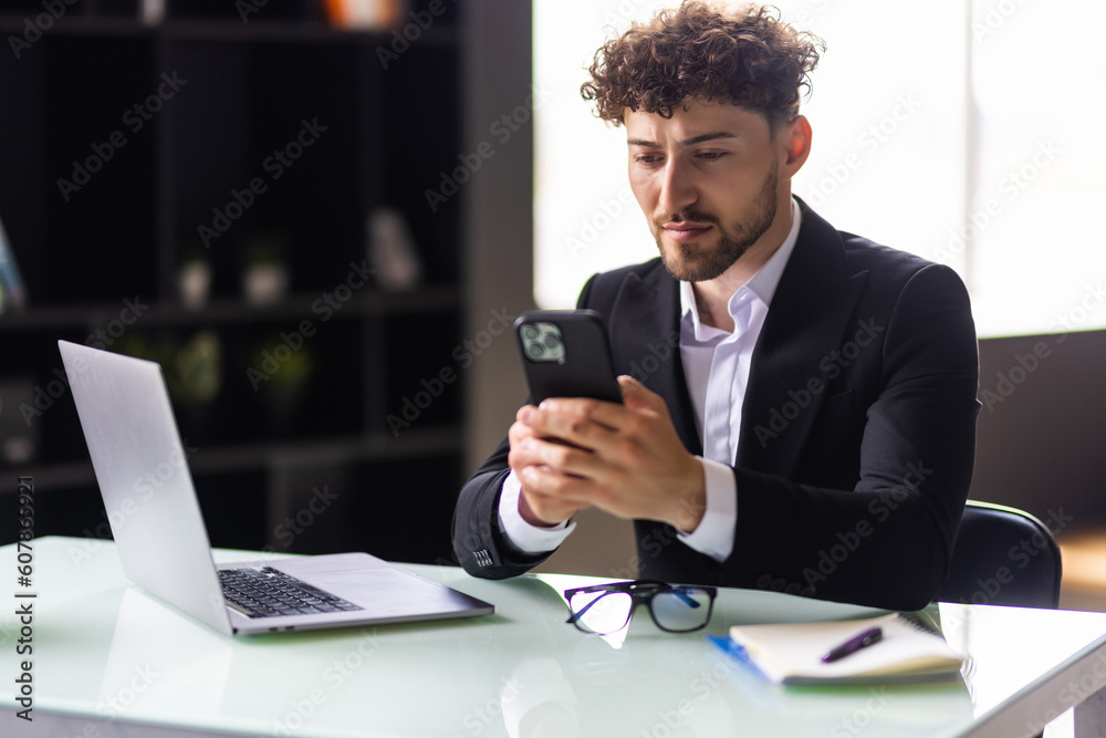 Young business man working at home with laptop and uses a smartphone in office Young business man working at home with laptop and uses a smartphone in office
