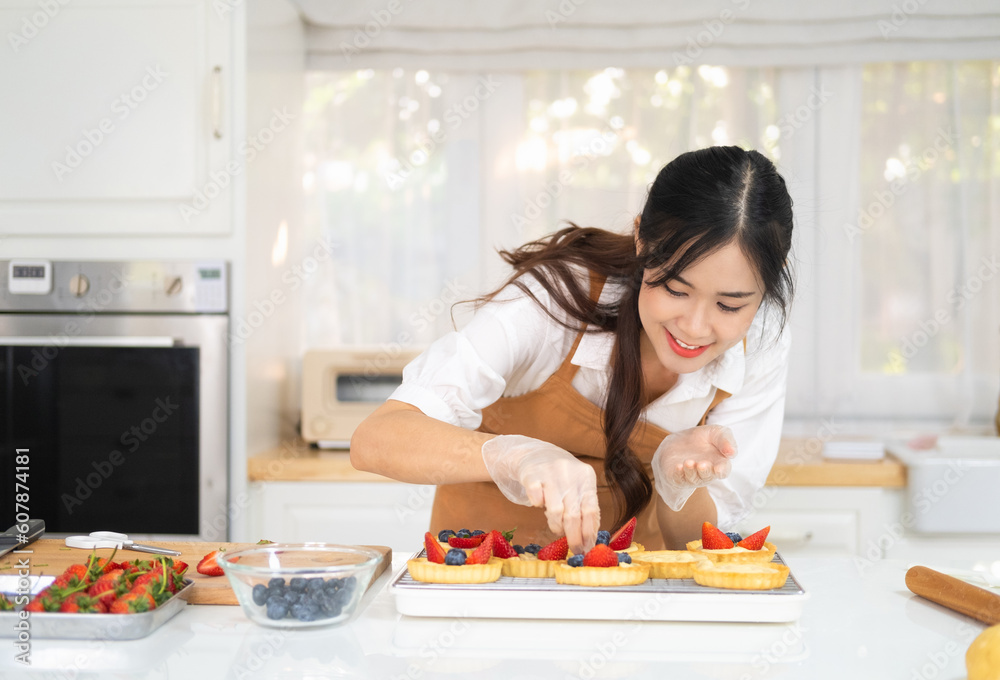 Happy young housewife hands in cooking gloves decorating freshly baked tart with blueberries strawberry fresh fruit.Woman chef baker wear apron making fruit tart. homemade bakery at home. Happy young housewife hands in cooking gloves decorating freshly baked tart with blueberries strawberry fresh fruit.Woman chef baker wear apron making fruit tart. homemade bakery at home.