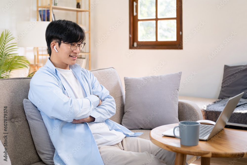 Happy satisfied millennial man using laptop at living room, working from home, reading message with good news, thinking, looking at screen, watching online webinar, training, making payment Happy satisfied millennial man using laptop at living room, working from home, reading message with good news, thinking, looking at screen, watching online webinar, training, making payment