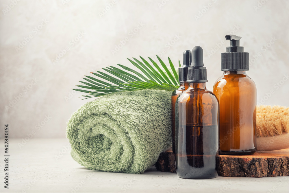 Bottles of dark amber glass with essential oil, cream, massage brush and tropical leaves Bottles of dark amber glass with essential oil, cream, massage brush and tropical leaves