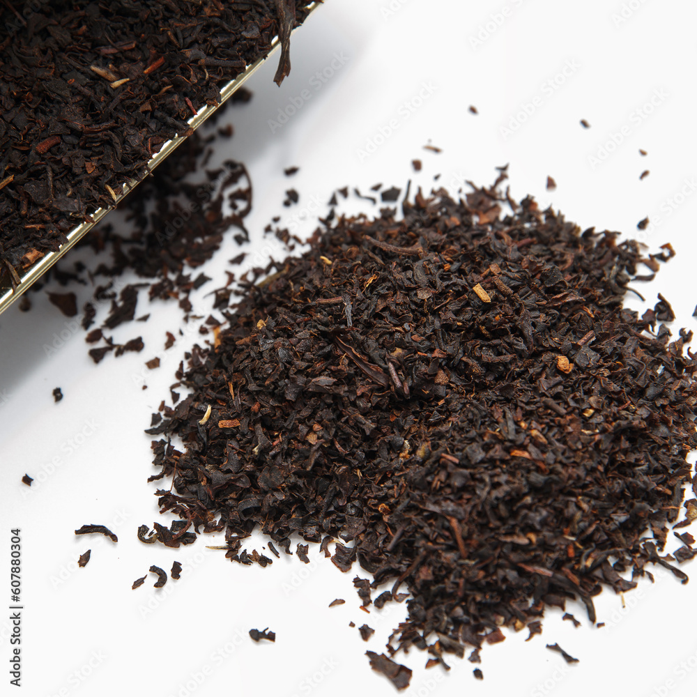 Fragrant dry large tea scattered from the package with bergamot on a white background. Tasty with traditional brewing Fragrant dry large tea scattered from the package with bergamot on a white background. Tasty with traditional brewing