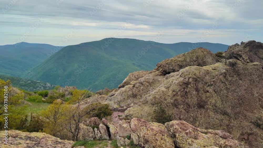 Panoramic view of the valley on top of the rocky ridge among the stones overlooking the beautiful valley. Outdoor and mountain hike background. Natural landscape in Bulgaria, Sliven Panoramic view of the valley on top of the rocky ridge among the stones overlooking the beautiful valley. Outdoor and mountain hike background. Natural landscape in Bulgaria, Sliven