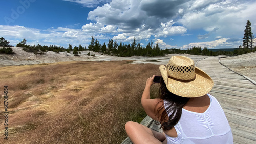 woman taking photos of Norris Geyser Basin in Yellowstone National Park photo
