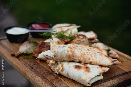 Chicken shawarma in pita bread with fresh vegetables, cream sauce and meat on a wooden background. Selective focus