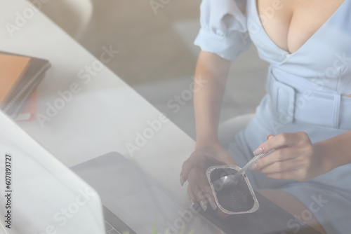 Smooth Focus young businesswoman is sitting at her desk alone in the morning eating brownies as she feels hungry while working. businessman concept take a snack break during work because of hunger